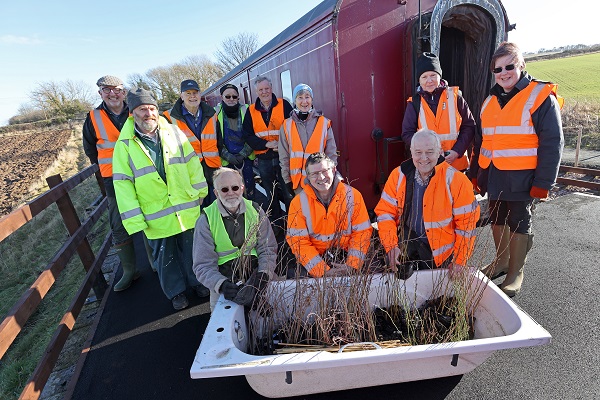 Aln Valley Railway volunteers stood on platform with tree saplings in front of steam engine