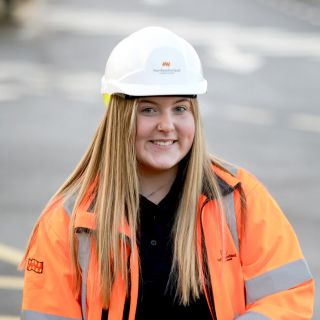 Civil Engineering Apprentice wearing a white hard hard looking into the camera