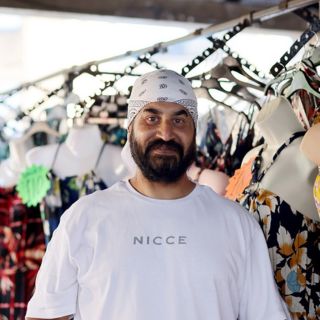 Market trader surrounded by clothes from his stall