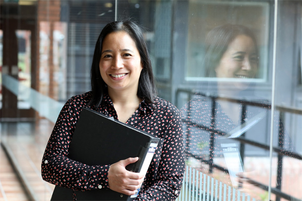 An apprentice holds a folder while smiling at County Hall