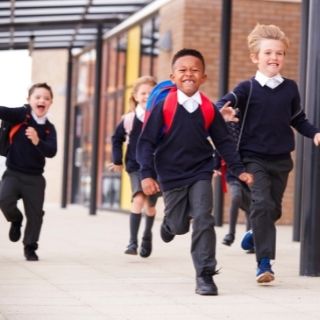 School children in uniform running on school grounds