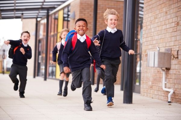 School children in uniform running on school grounds