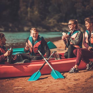 A group of teenagers sitting in a kayak, laughing at a joke