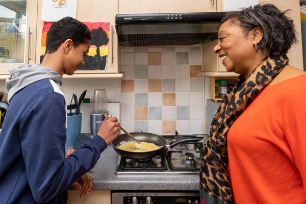 A teen being taught how to cook with a foster parent