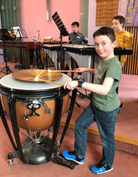 A young boy playing a large drum