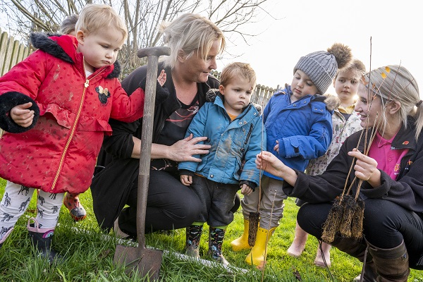 Children at Spring Nursery planting trees with nursery staff Janine and Abbie
