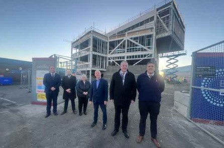 A group of people standing in front of construction site for the new Energy central hub