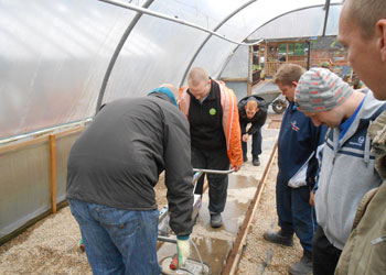 Gardeners fit a new bed in a greenhouse