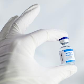 A gloved hand holding a vaccine vial