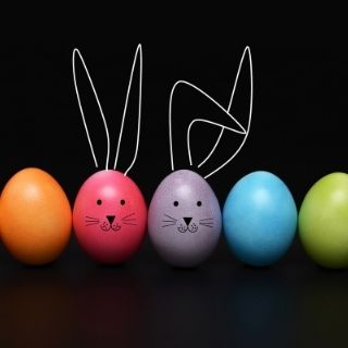 6 coloured eggs with 2 that have a rabbits face drawn on