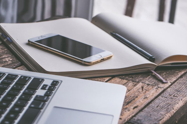 Laptop next to a mobile phone on a notepad