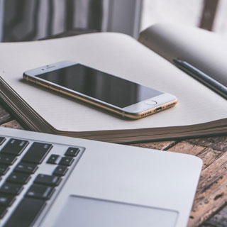 Laptop next to a mobile phone on a notepad