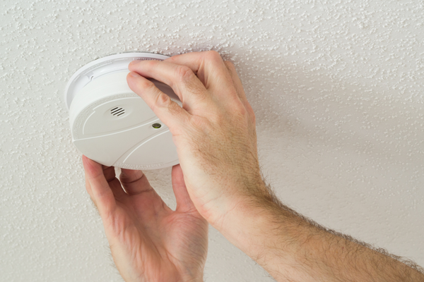 A person installing a fire alarm on the ceiling 