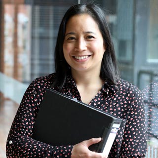 An apprentice holds a folder while smiling at County Hall