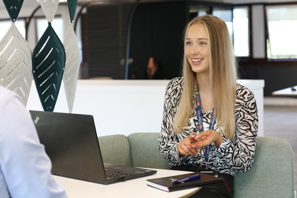 Apprentice Niamh sitting behind a laptop talking to someone out of shot