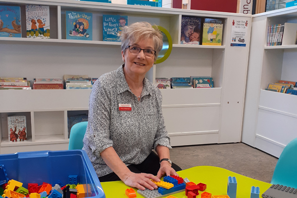 Libraries volunteer Linda sitting at a table with Lego 