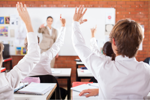 Children raise their hands in a classroom