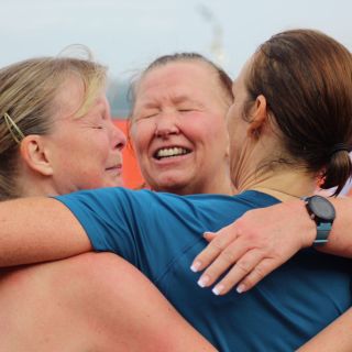 Three female runners hugging