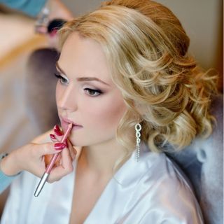 Bride looking off camera getting makeup professionally applied