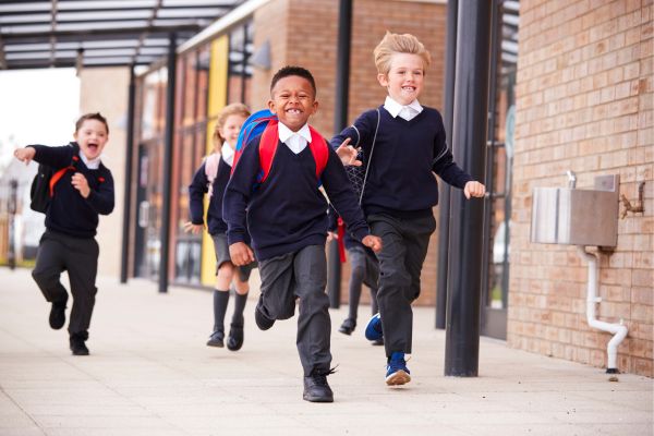 A group of school children in uniform running and smiling 