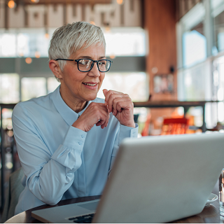 A smiling woman looking at her laptop.