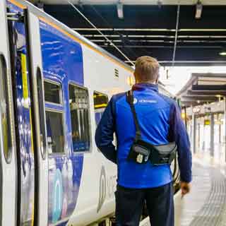 A Northern conductor standing by a train