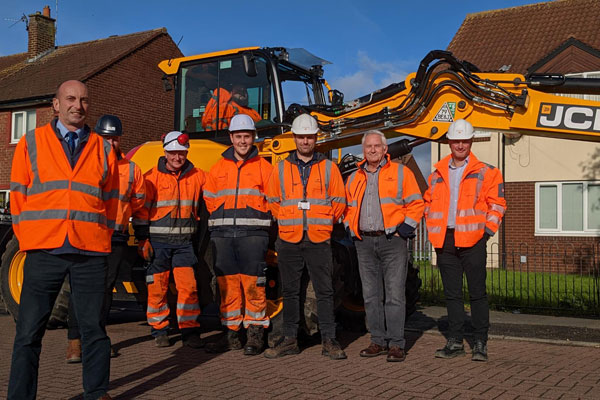 Coucnillors and county council staff in front of a pothole repairing machine