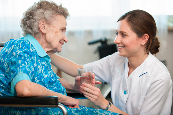 A homecare worker giving an older person a glass of water