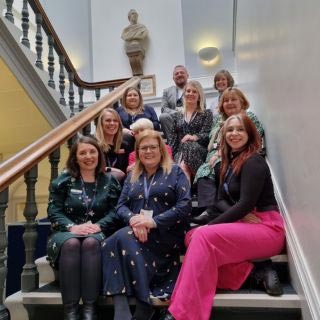 Northumberland Registration team sat on a staircase inside Morpeth Town Hall