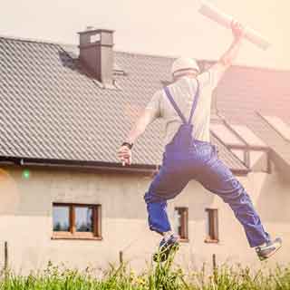  A builder jumping in the air in front of a new house