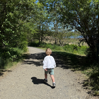 A little boy exploring Druridge Bay Country Park- image taken from the back, with lake in the background