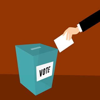 A hand putting a vote inside a ballot box