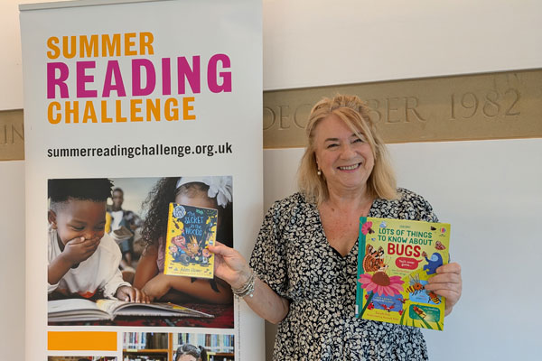 Councillor Wendy Pattison in front of a summer reading challenge sign