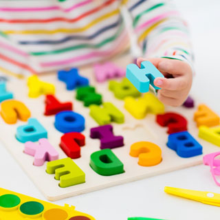 child learning alphabet with wooden letters