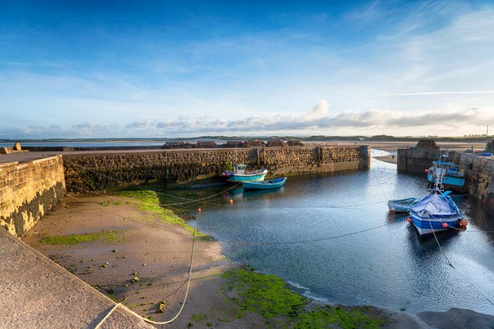 Beadnell harbour with it's stone ports. The tide is out so the boats docked are low to the ground.