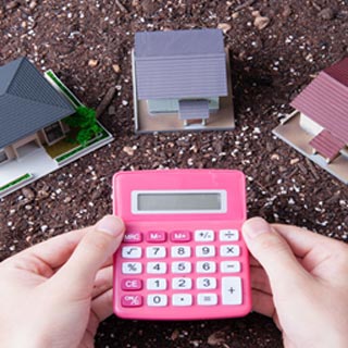 A person with a calculator with toy houses