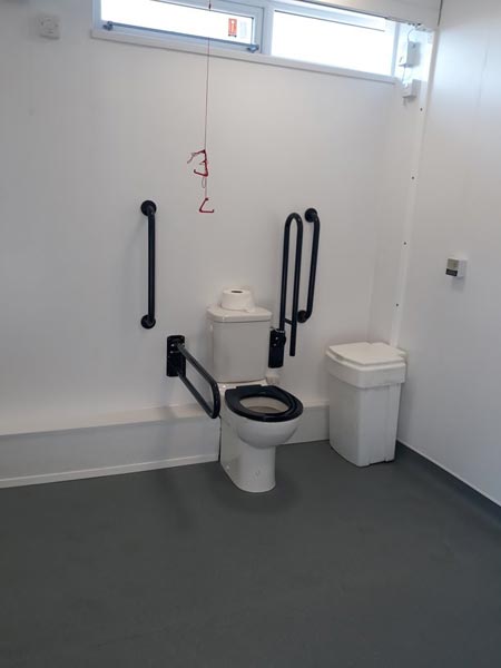 Toilet in the accessible toilet area. It has handles for ease of use.