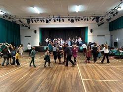 Students dancing in a hall to a band playing music