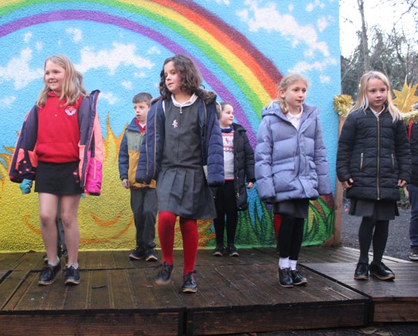 A group of school children clog dancing on a stage