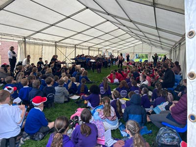 Inside the tent with a large group of school children sitting listening to a band perform.