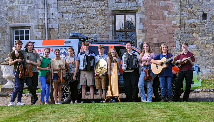 The band with their instruments in front of the mountain rescue truck